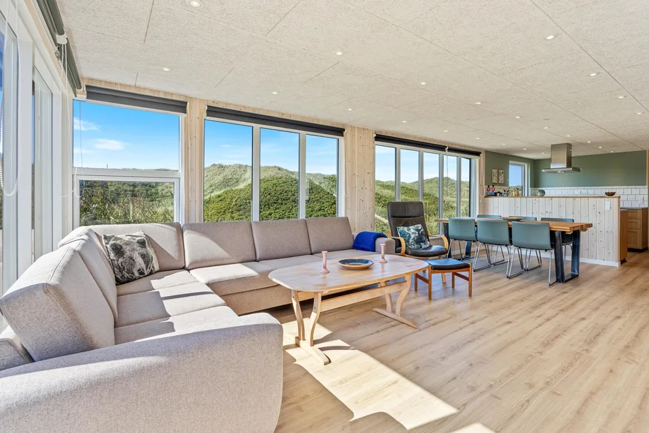 Una sala y comedor de planta abierta con grandes ventanas y vistas a colinas verdes.