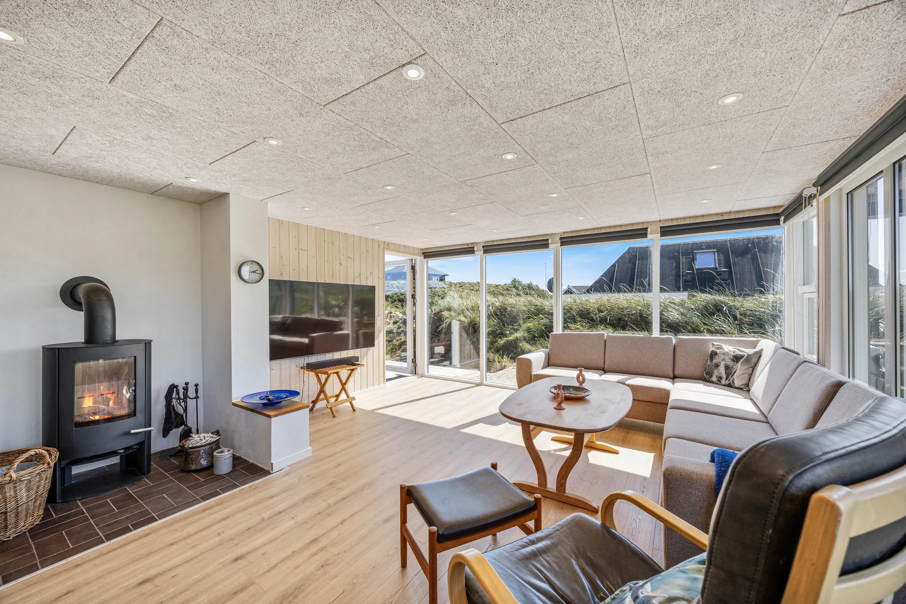 Una sala de estar luminosa con asientos, una mesa de centro y grandes ventanas.
