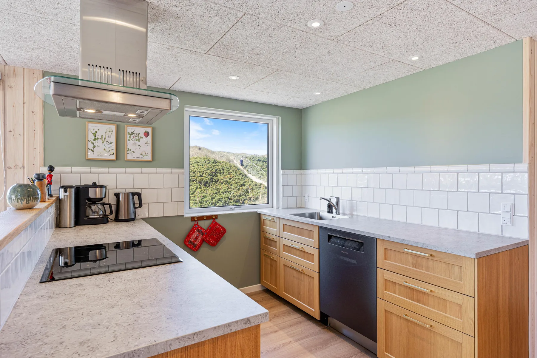 Una cocina moderna con armarios de madera, una placa de cocción y una ventana con vistas a la vegetación.