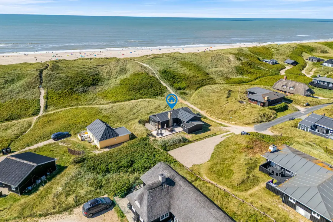Vista aérea de casas entre dunas costeras junto a la playa.