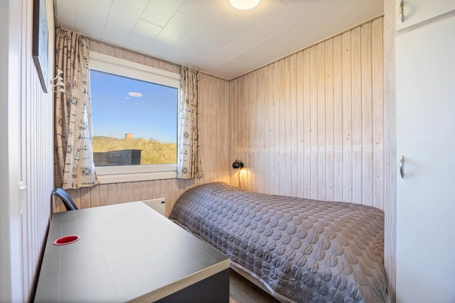 Un dormitorio pequeño con una cama junto a una ventana y un escritorio.
