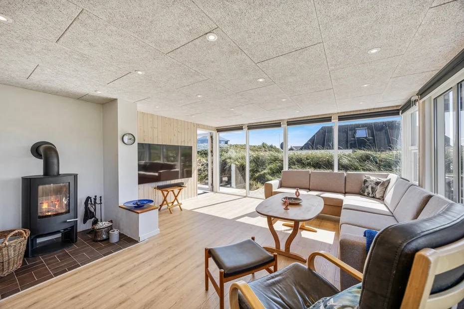 Una sala luminosa con asientos, grandes ventanas y una chimenea.