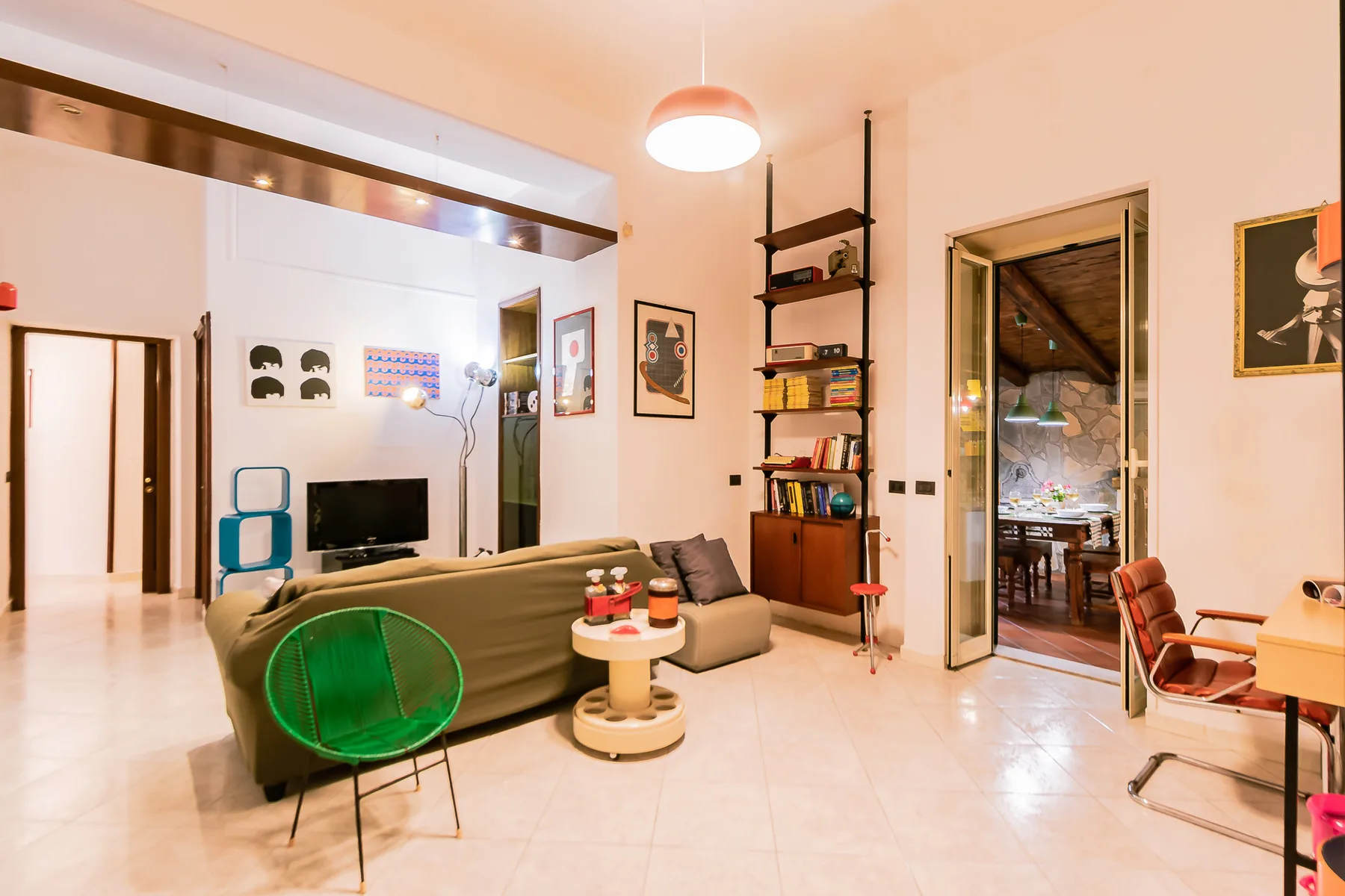 A bright living room with seating, a television, and an open doorway to a dining area.