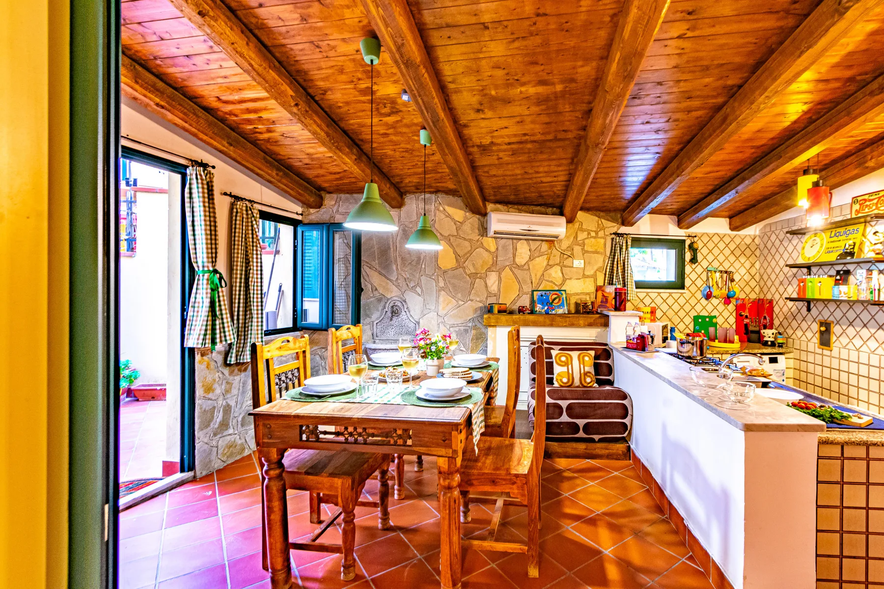 A rustic kitchen and dining area with a wooden table beneath a timber ceiling.
