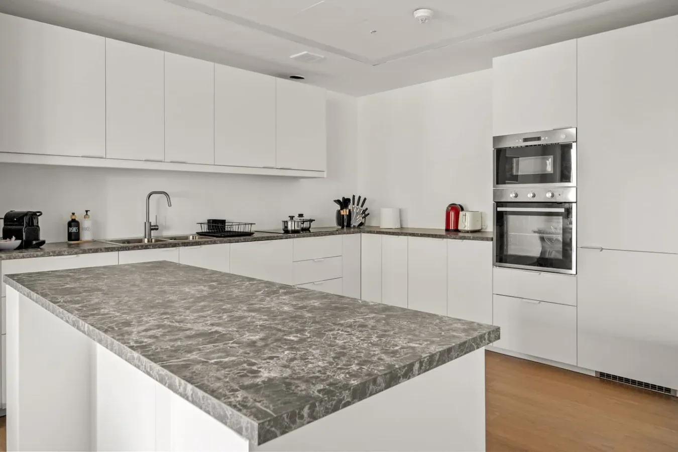 Una cocina moderna con armarios blancos y una gran isla de piedra.