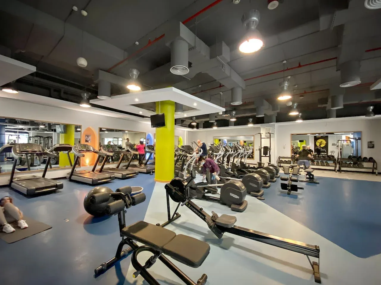 Un gimnasio con máquinas de ejercicio y equipo de entrenamiento con pesas.