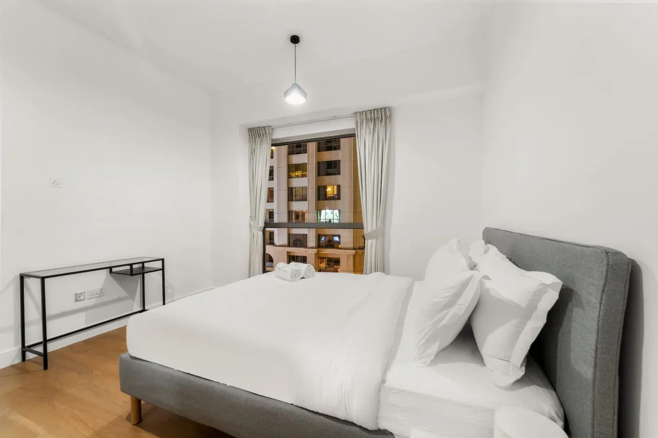 Un dormitorio luminoso con una cama bien arreglada y una ventana con cortinas.