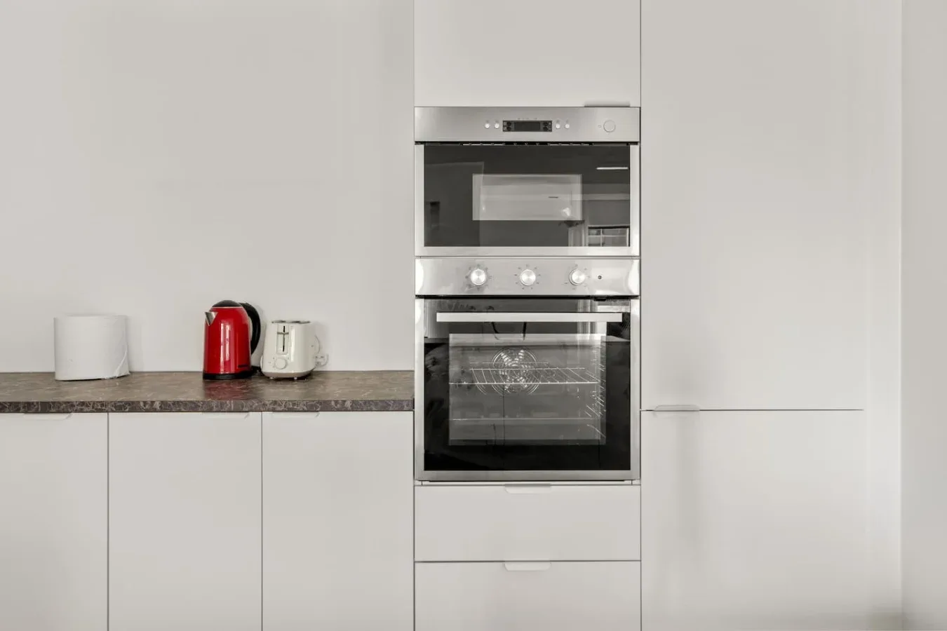 Una cocina moderna con hornos empotrados y pequeños electrodomésticos sobre la encimera.