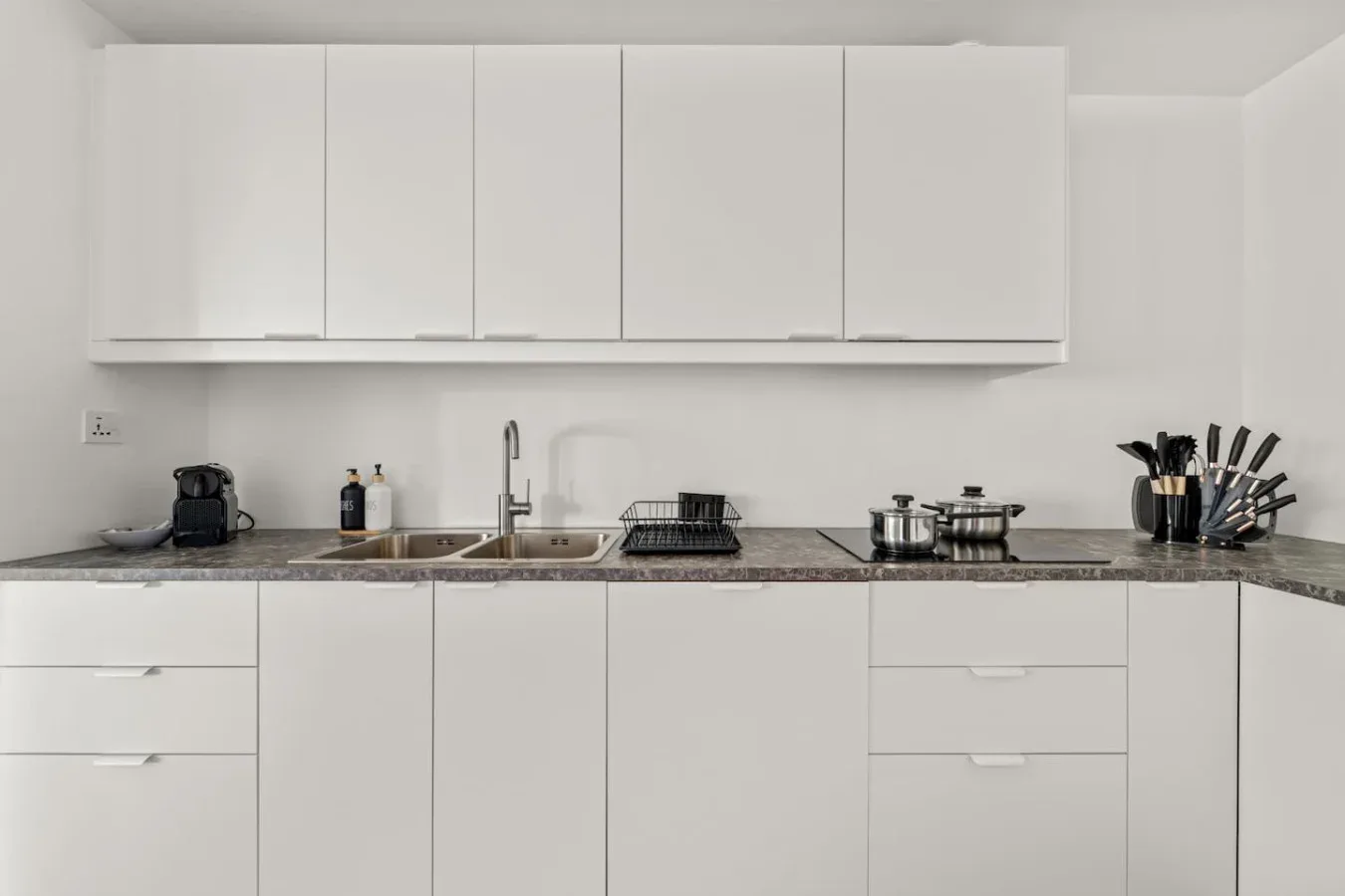 Una cocina luminosa con gabinetes blancos, una encimera y un fregadero.