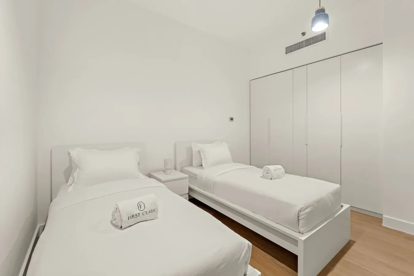 Un dormitorio luminoso con dos camas y ropa de cama blanca.