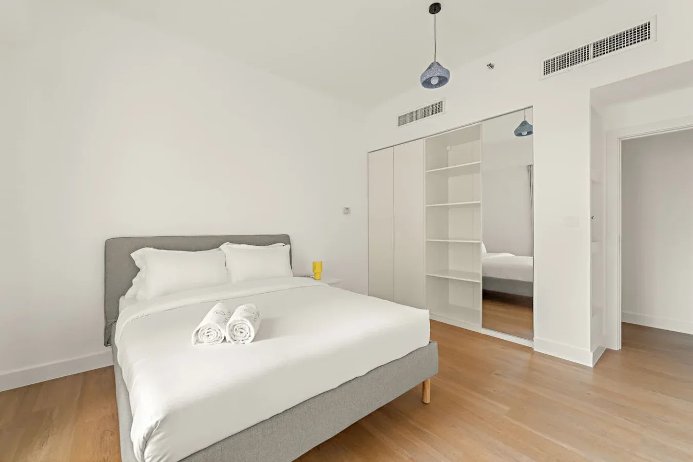 Un dormitorio luminoso con una cama tendida junto a un armario con espejo.