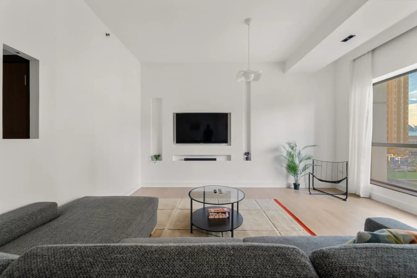 Sala de estar luminosa con televisor, mesa de centro y asientos.
