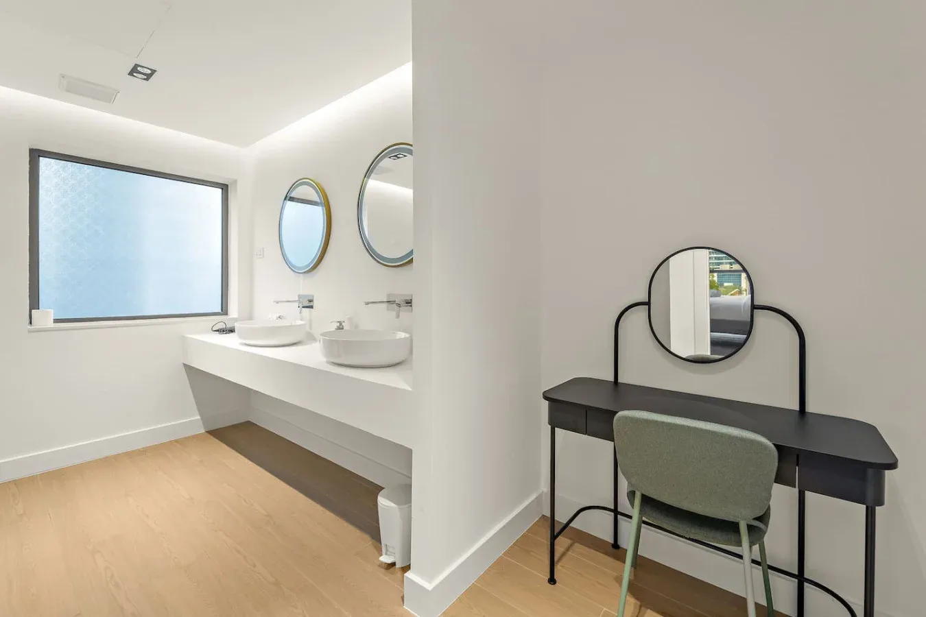 Un baño luminoso con un tocador largo y una zona de escritorio separada.