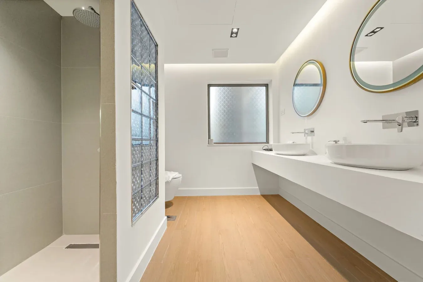 Un baño moderno con ducha a ras de suelo y un largo lavabo.