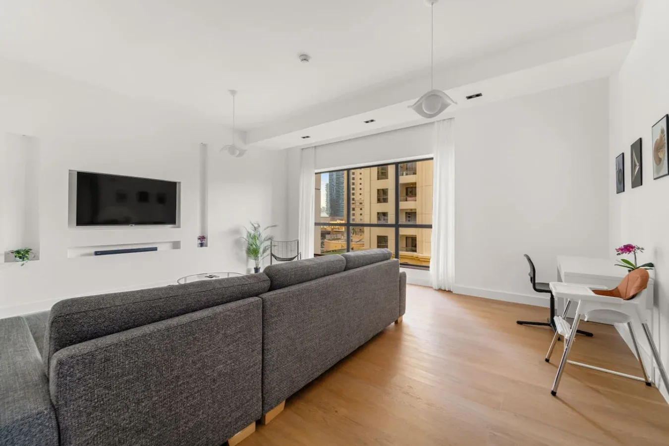 Una sala luminosa con asientos grises y grandes ventanas con vista a edificios cercanos.
