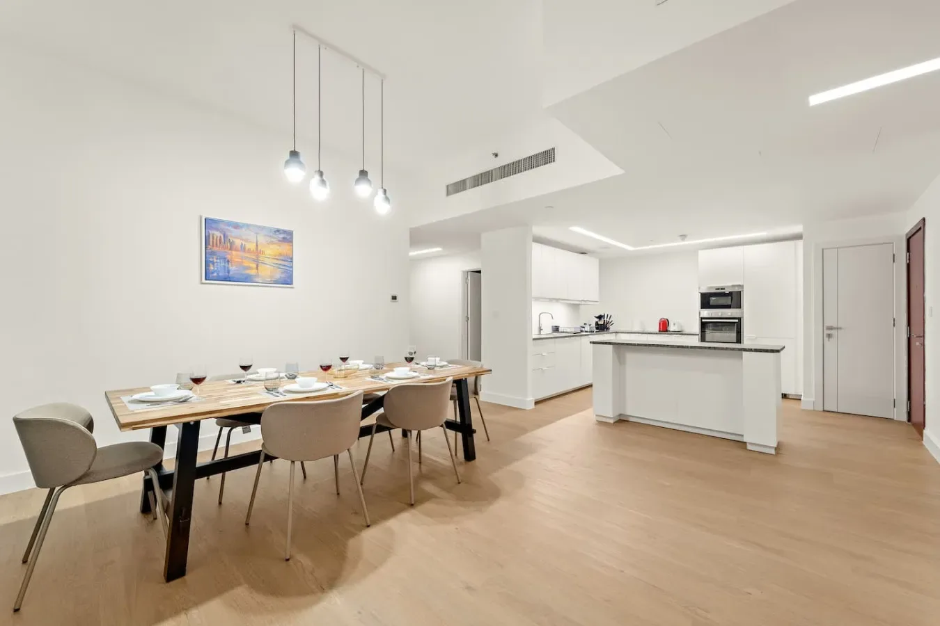 Comedor y cocina de planta abierta, luminosos, con una mesa larga.