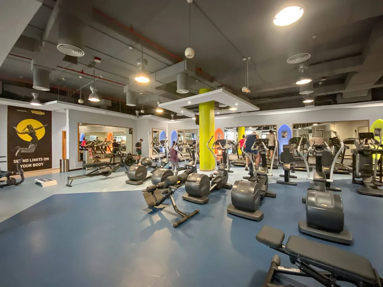Un gimnasio con máquinas de ejercicio y equipo de entrenamiento por todo el espacio.