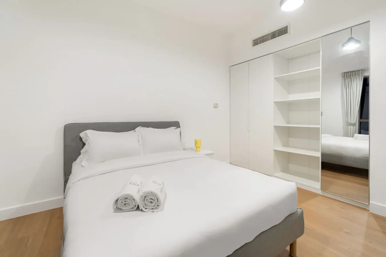 Un dormitorio luminoso con una cama tendida y estanterías empotradas.