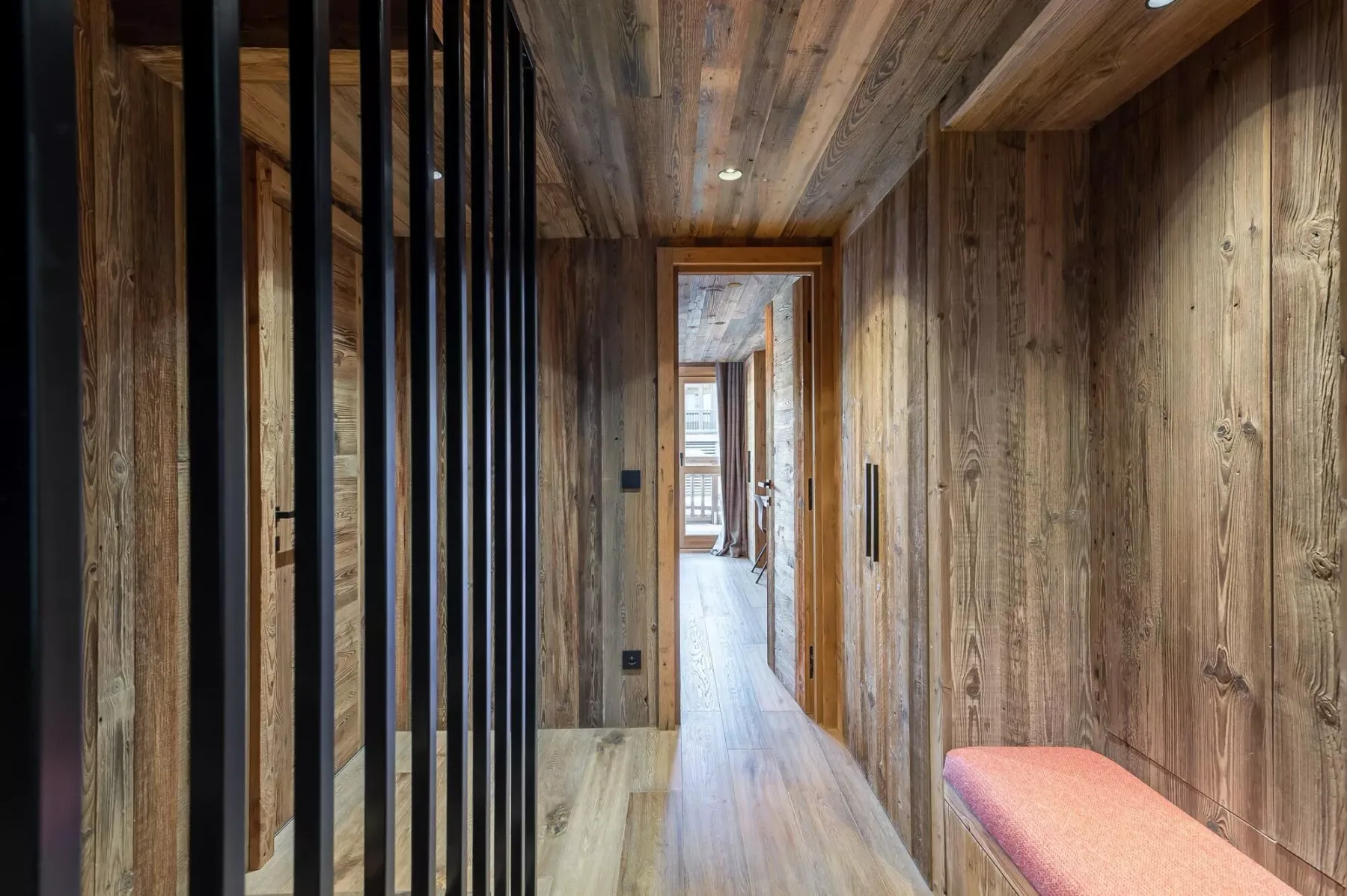 Un pasillo revestido de madera con un banco estrecho junto a la pared.