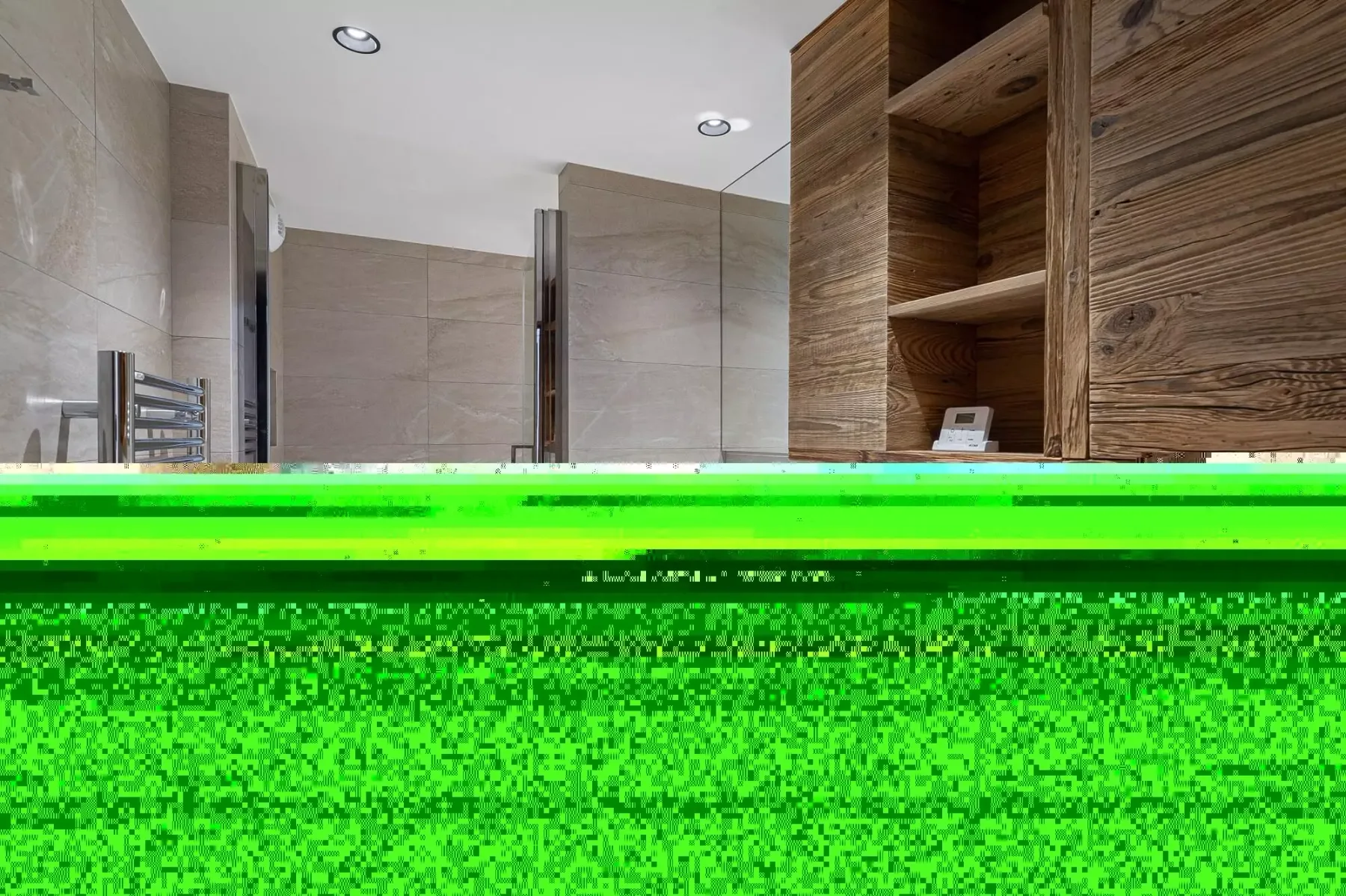 Un baño con azulejos, un toallero calefactable y estanterías de madera.