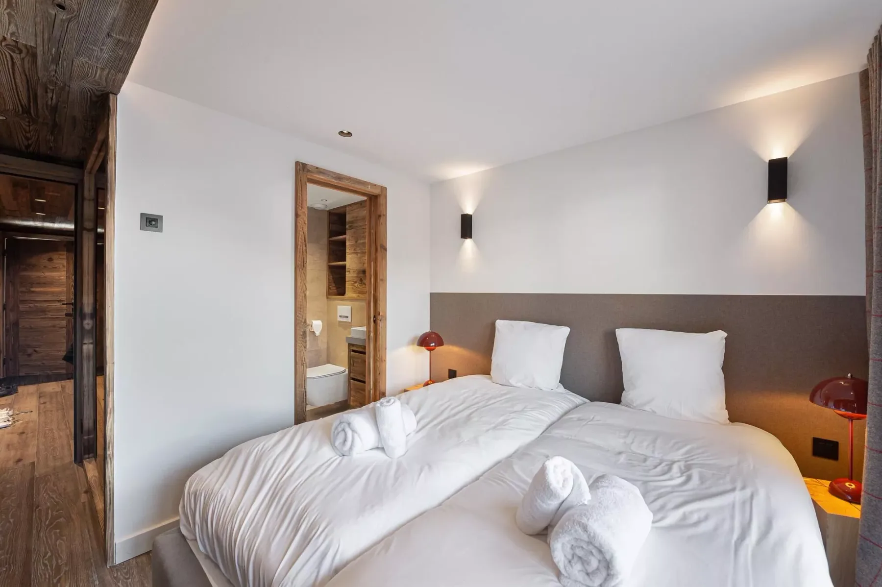 Un dormitorio con camas vestidas de blanco y luces en la pared.
