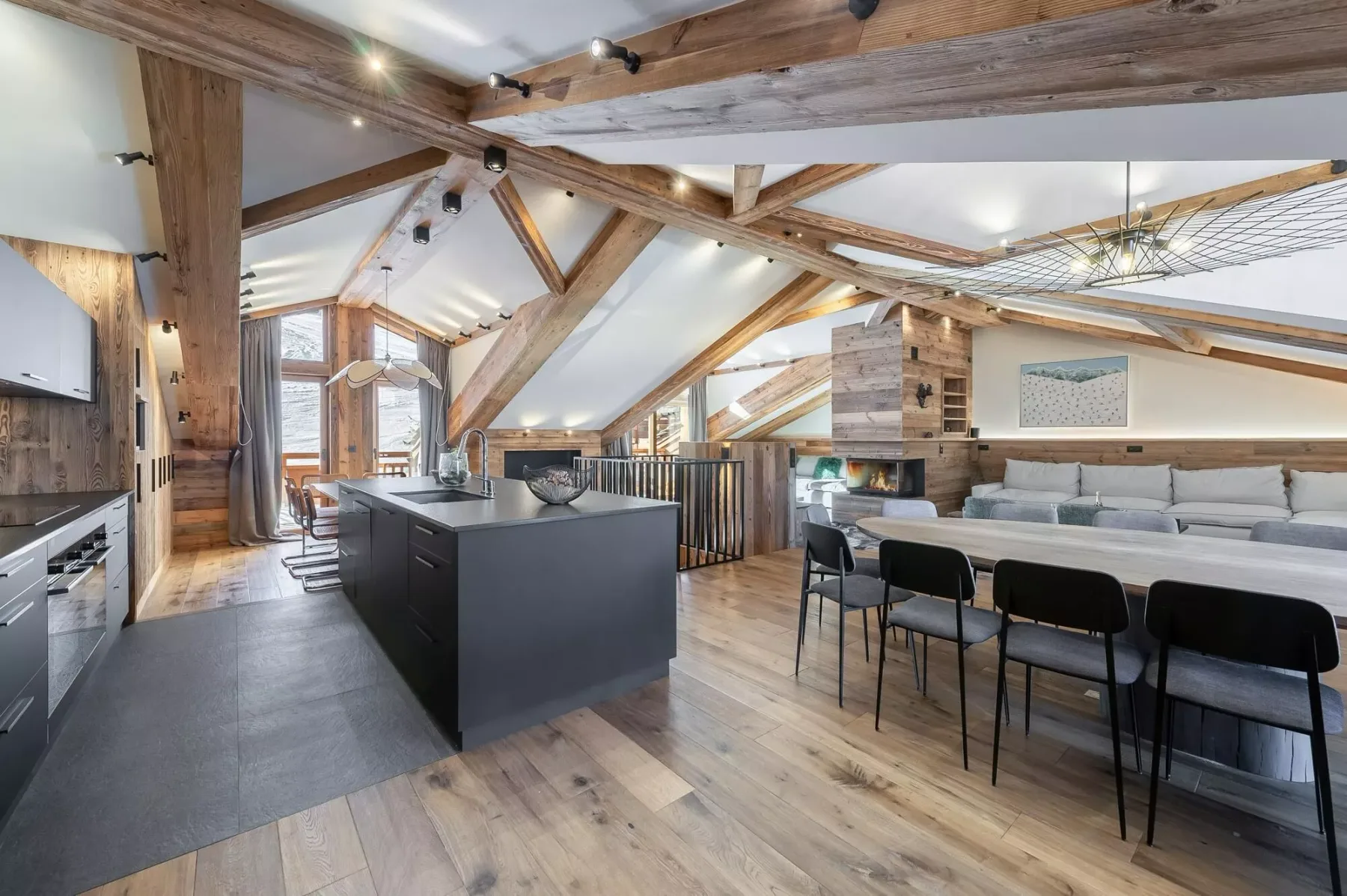 Una cocina y comedor de planta abierta con vigas de madera expuestas y una mesa larga.