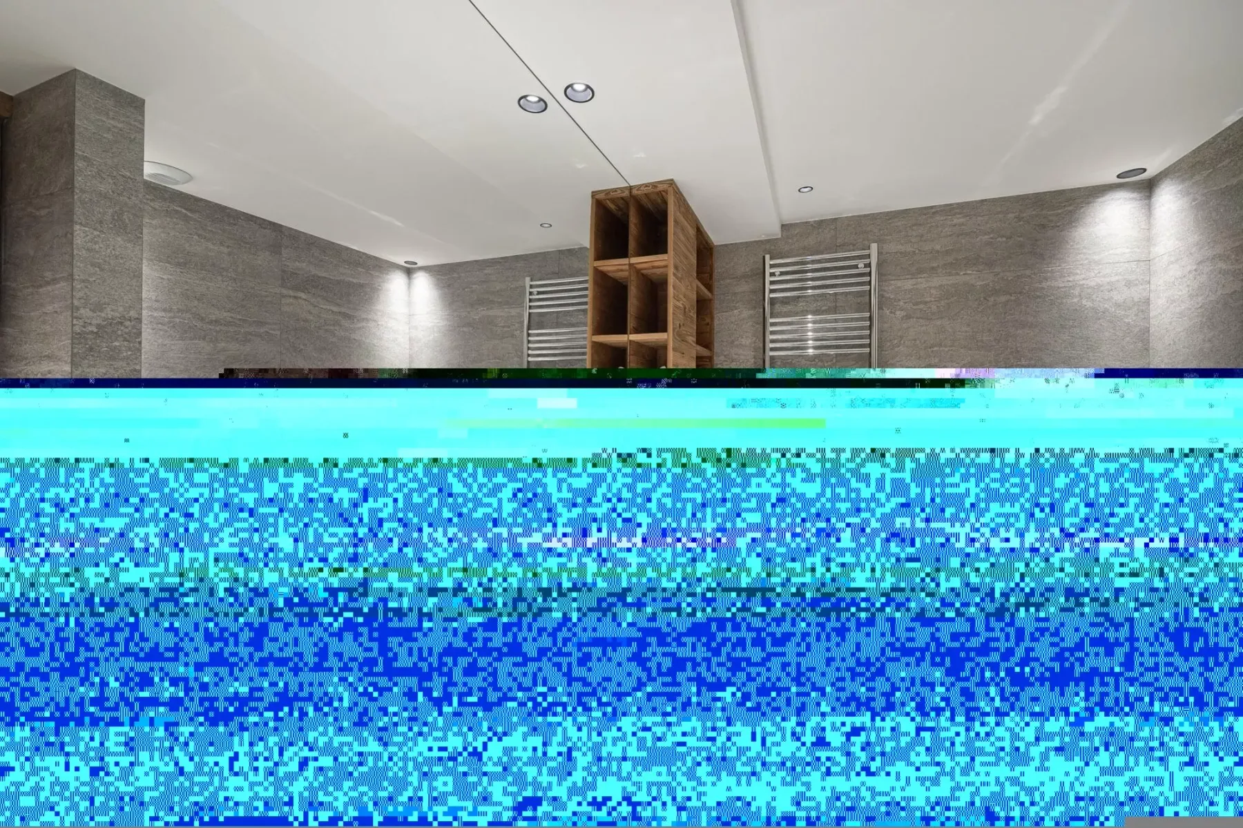 Un baño moderno con paredes grises, estantes y toalleros.
