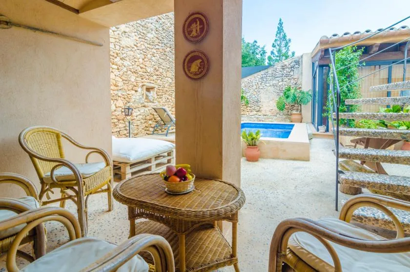 A covered patio with wicker seating and a small swimming pool in the courtyard.