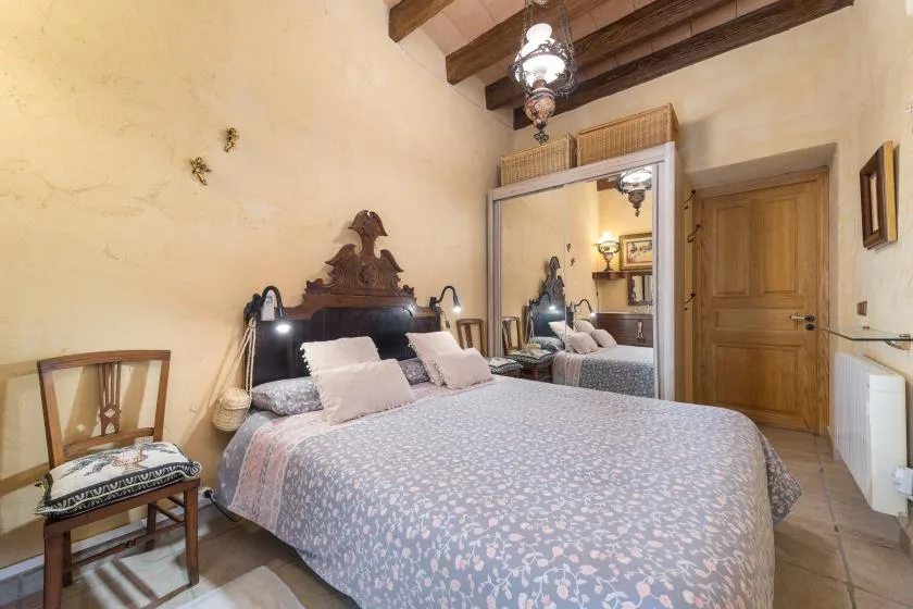 A bedroom with a large bed, mirrored wardrobe, and exposed ceiling beams.