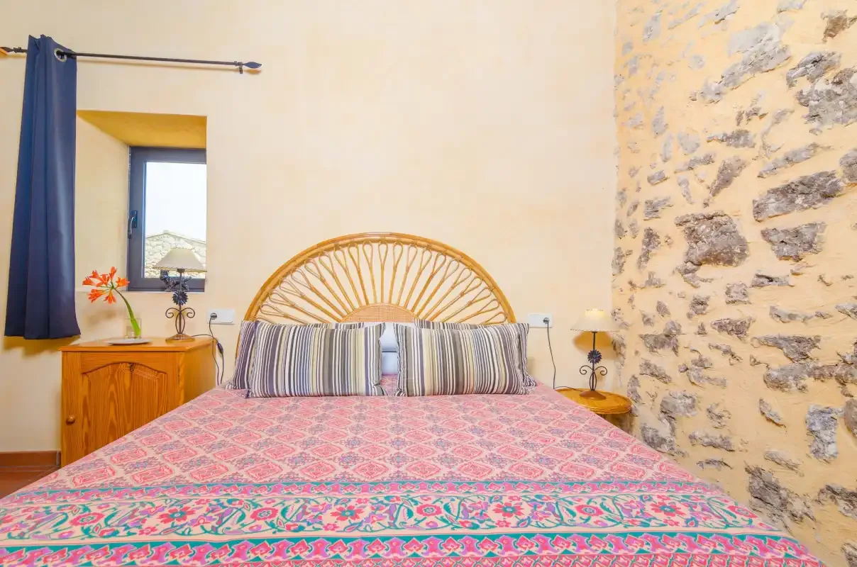 A bedroom with a patterned bedspread and woven headboard.