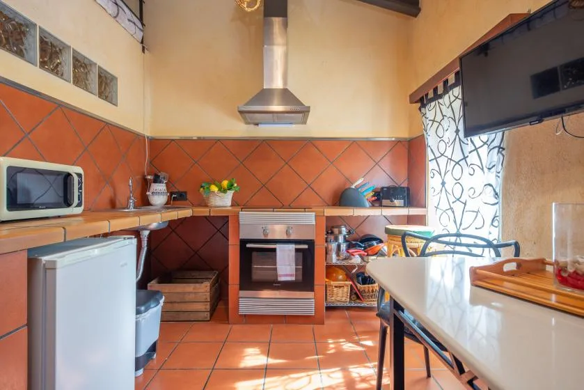 A tiled kitchen with a stove, countertop appliances, and a dining table.
