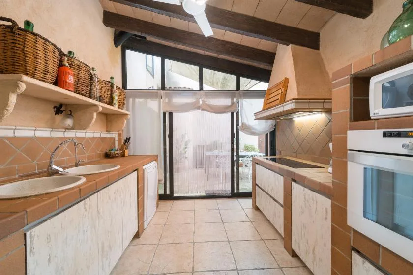 A tiled kitchen with counters, a sink, and a glass door.