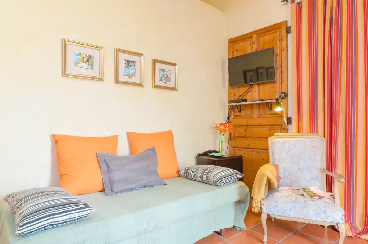 A sitting area with a daybed, patterned cushions, and a television.