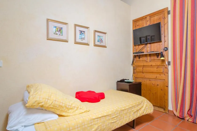 A bedroom with a bed, framed pictures, and a wall-mounted television.