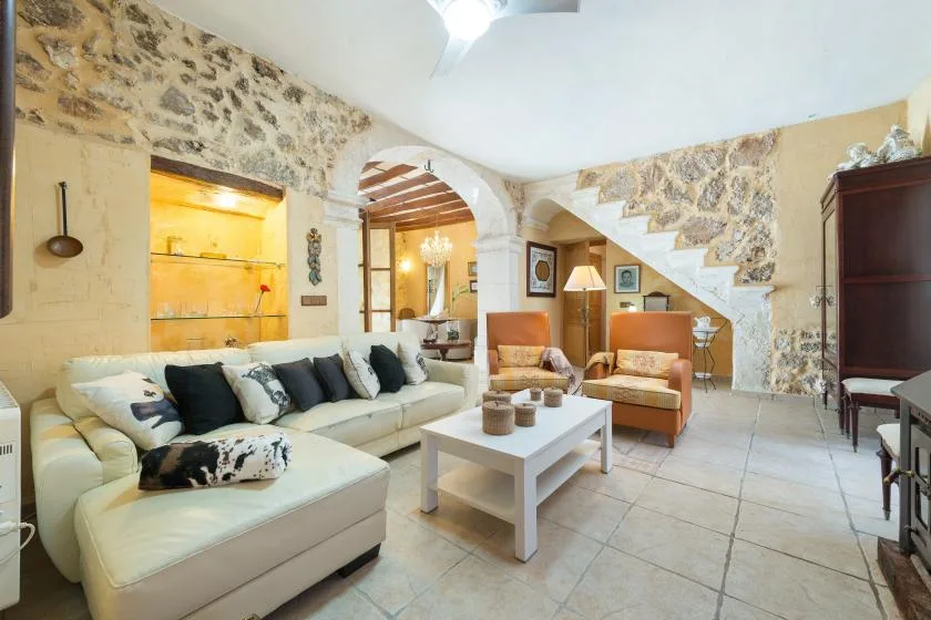 A living room with pale seating, two armchairs, and an arched opening.