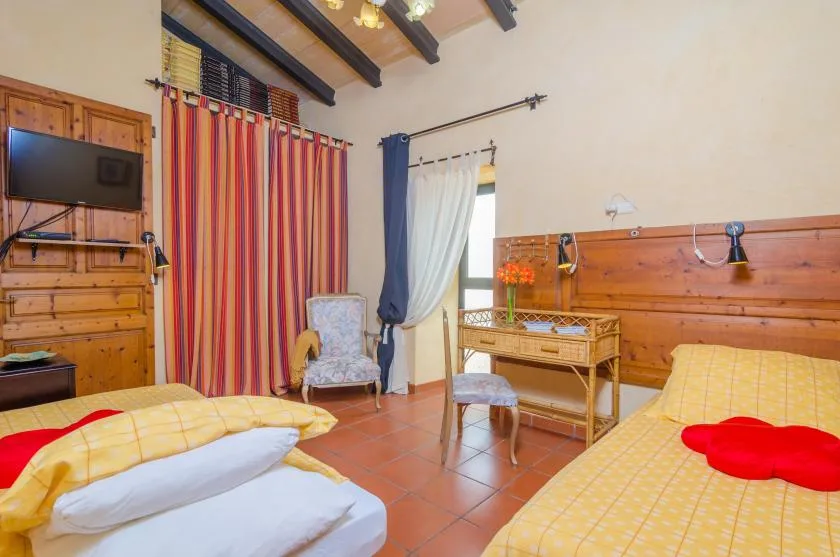 A bedroom with two beds, striped curtains, and wooden furnishings.