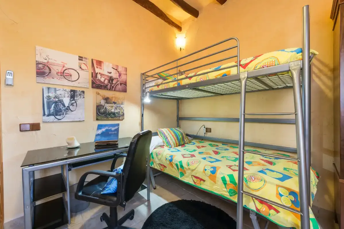 A bedroom with colorful bedding on a bunk bed beside a desk.