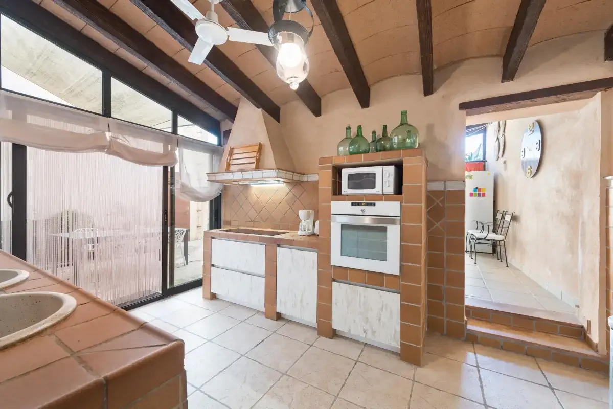 A kitchen with a built-in oven and a counter beneath exposed ceiling beams.