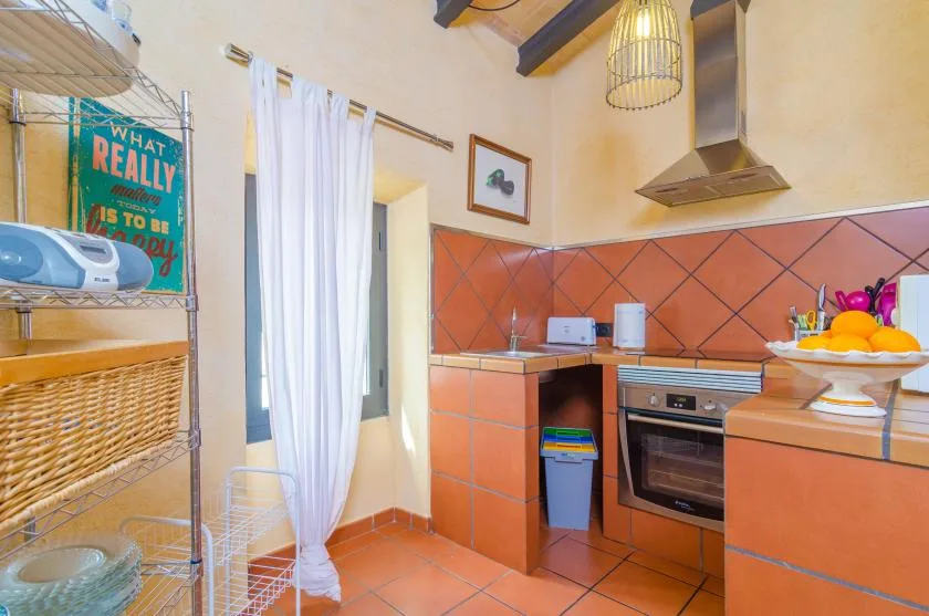 A tiled kitchen with a built-in oven, countertop, and hanging pendant light.