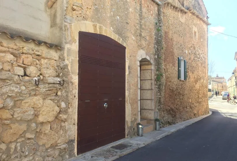 A stone building façade with a large dark wooden door beside a narrow street.