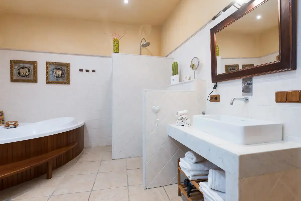 A bathroom with a bathtub, shower area, and sink.