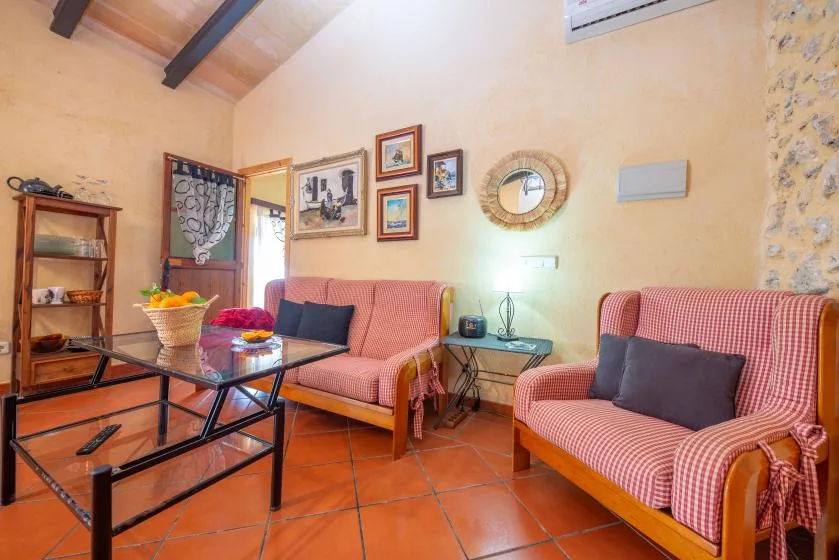 A living room with patterned seating, a glass coffee table, and framed pictures.