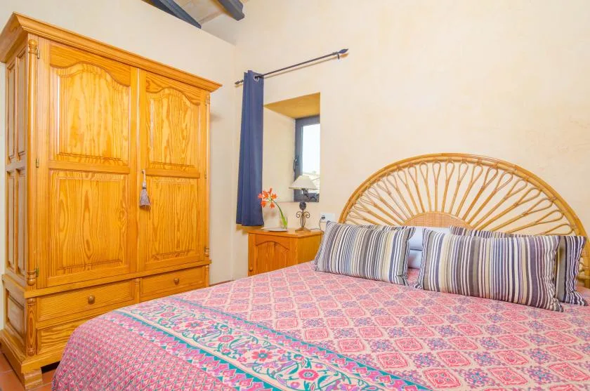 A bedroom with a patterned bedspread and a woven headboard.