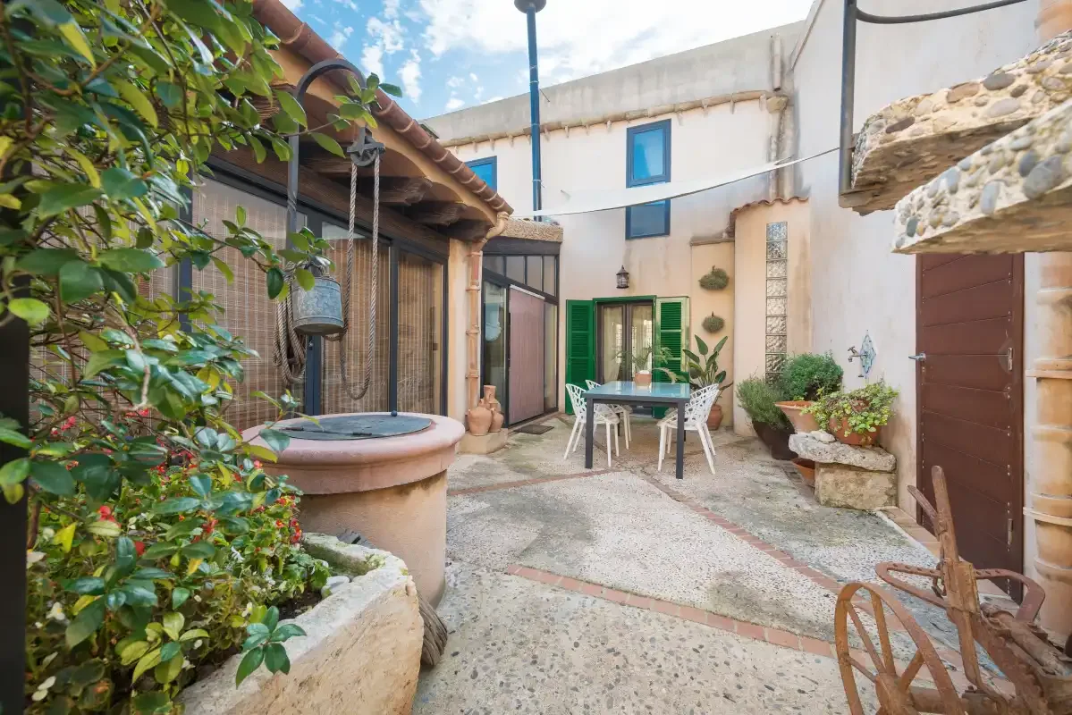 A courtyard with a small round hot tub, outdoor seating, and potted plants.