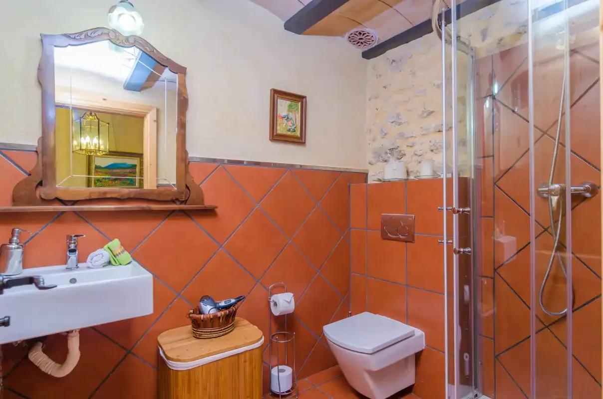 A bathroom with a sink, mirror, toilet, and glass shower.