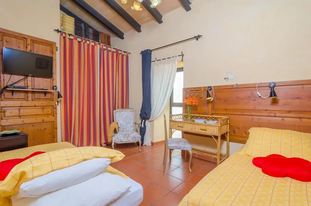 A bedroom with two beds, wooden furnishings, and colorful curtains.