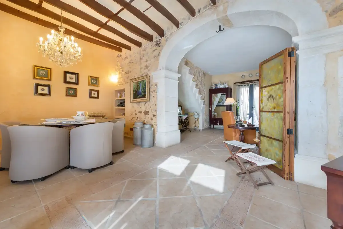 A bright dining area opens through a large arch into a furnished living space.