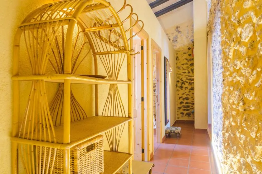 A narrow interior hallway with terracotta-colored tile flooring and open shelving.