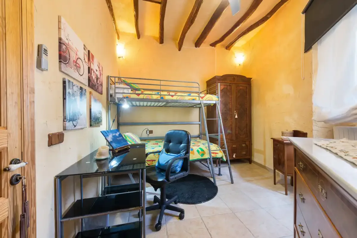 A bedroom with bunk beds, a desk, and a wardrobe.