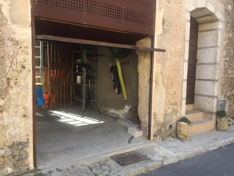 An open garage entrance reveals a dim interior with tools and equipment.